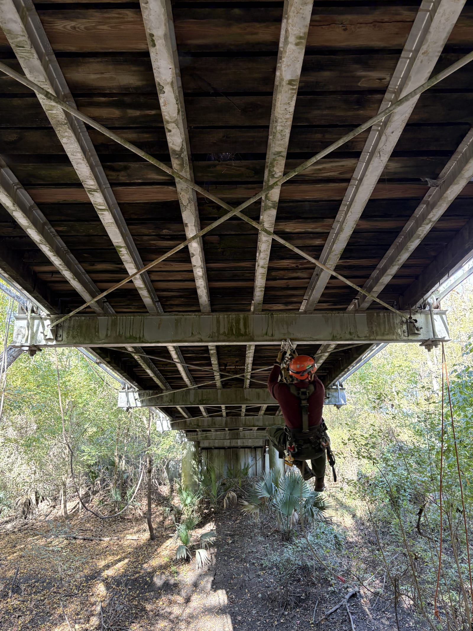 Inspector on rope-access gear inspecting the underside of a bridge superstructure