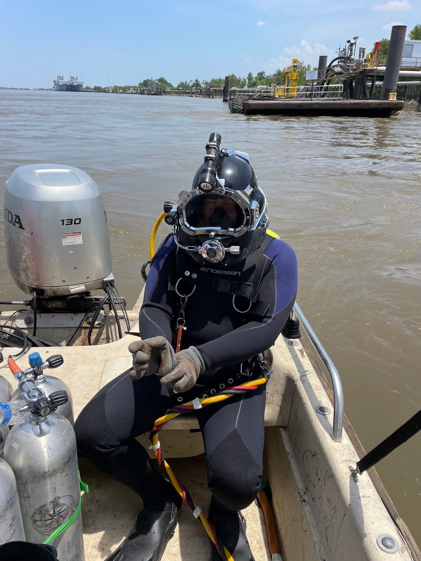 Commercial diver in surface-supplied diving gear on a dive boat before an underwater inspection
